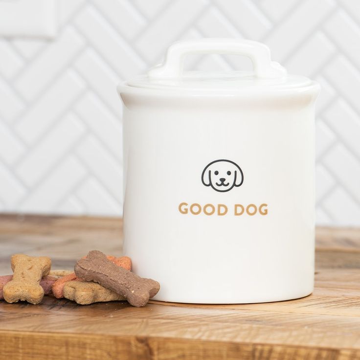 a white canister sitting on top of a wooden table next to some dog treats