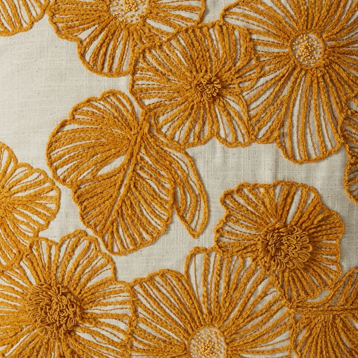 closeup of an embroidered fabric with flowers in yellow and white colors on the bottom