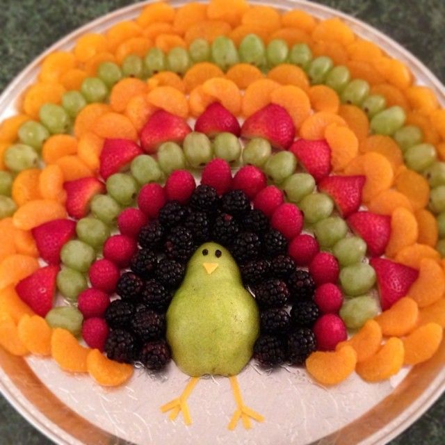 a turkey made out of fruits and vegetables on top of a white plate with a green bird