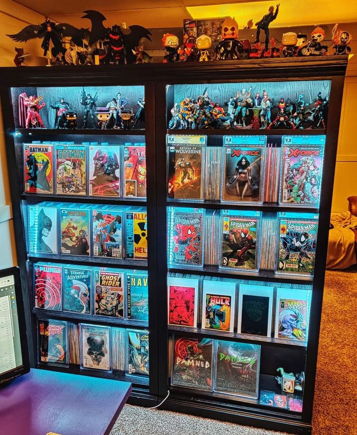 a display case filled with comic books on top of a table next to a laptop computer