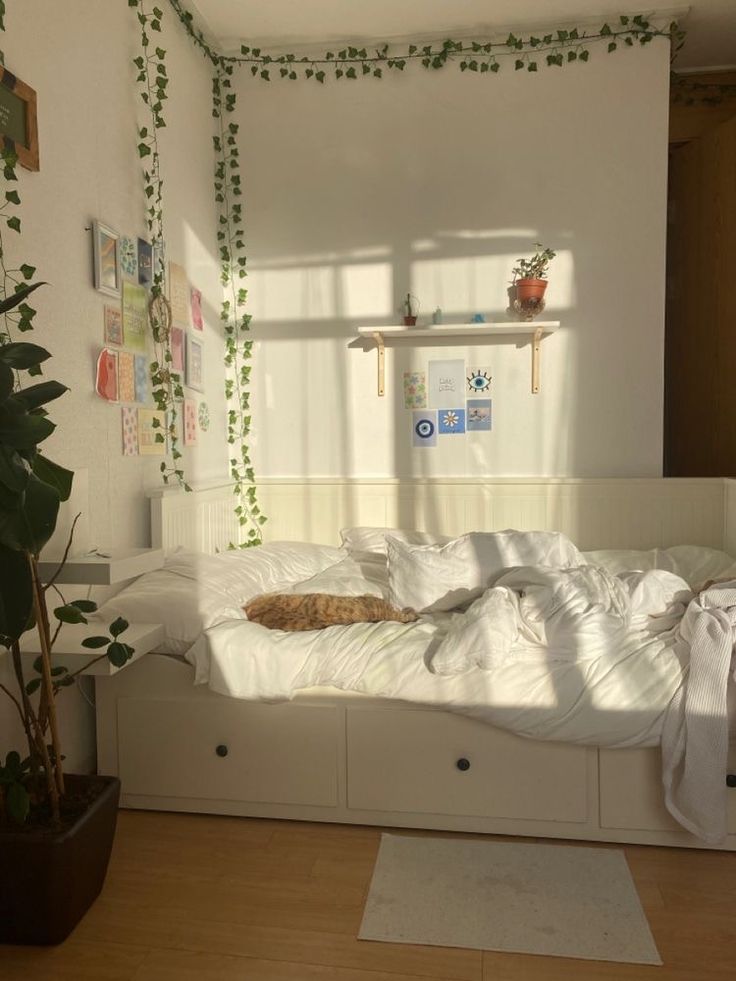 a cat laying on top of a white bed in a room with wooden flooring