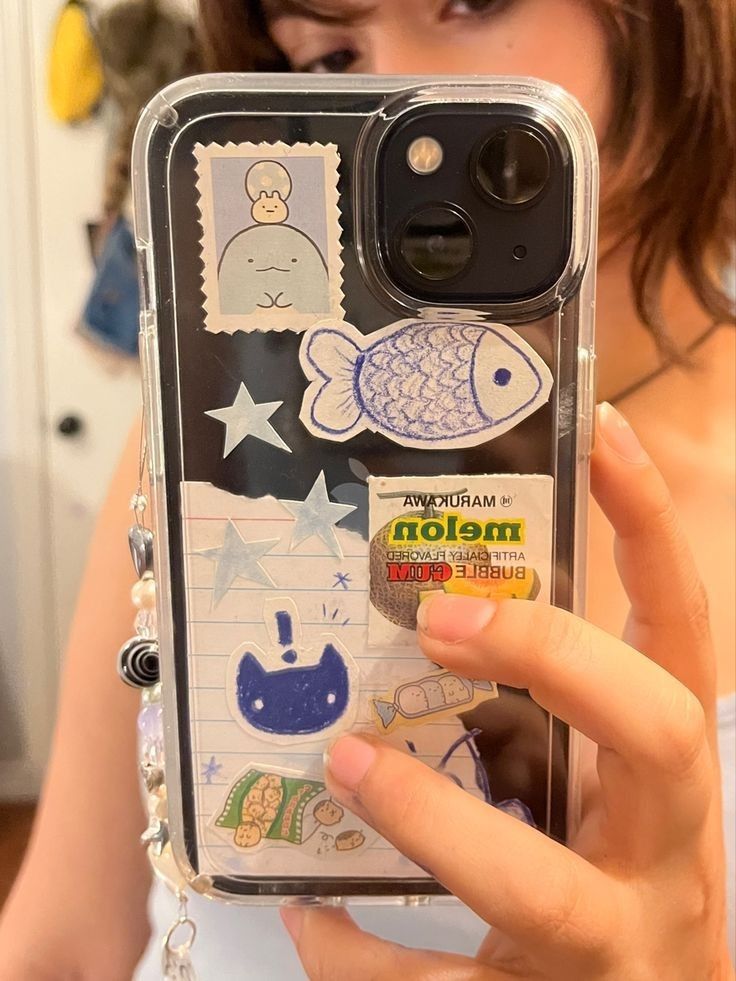 a woman holding up a cell phone case with stickers on the back of it