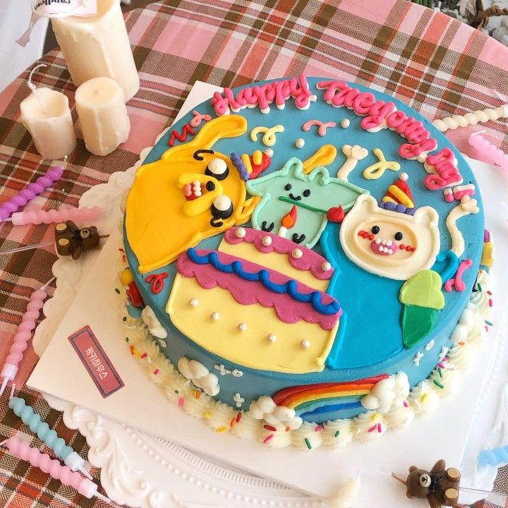 a birthday cake decorated with cartoon characters on top of a table next to candles and other decorations