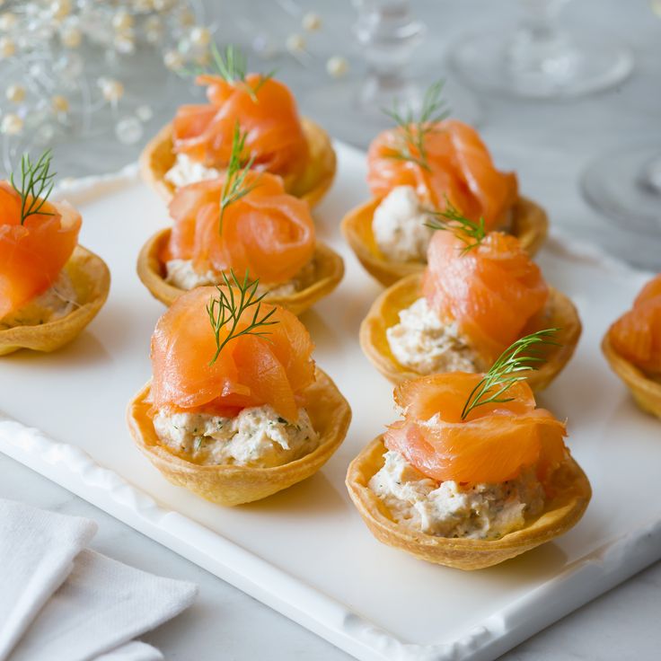 small appetizers with smoked salmon and cream cheese are arranged on a white platter