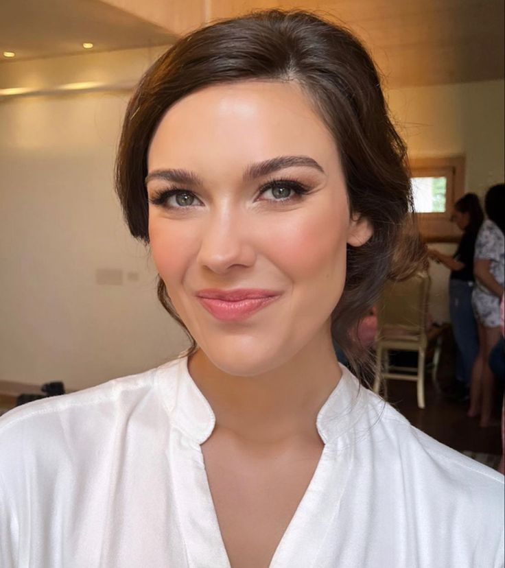 a close up of a person wearing a white shirt and looking at the camera with a smile on her face