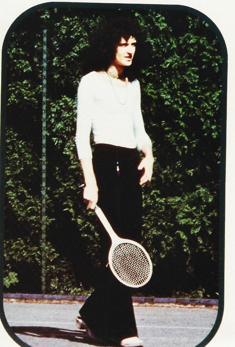 a woman holding a tennis racquet on top of a tennis court with trees in the background