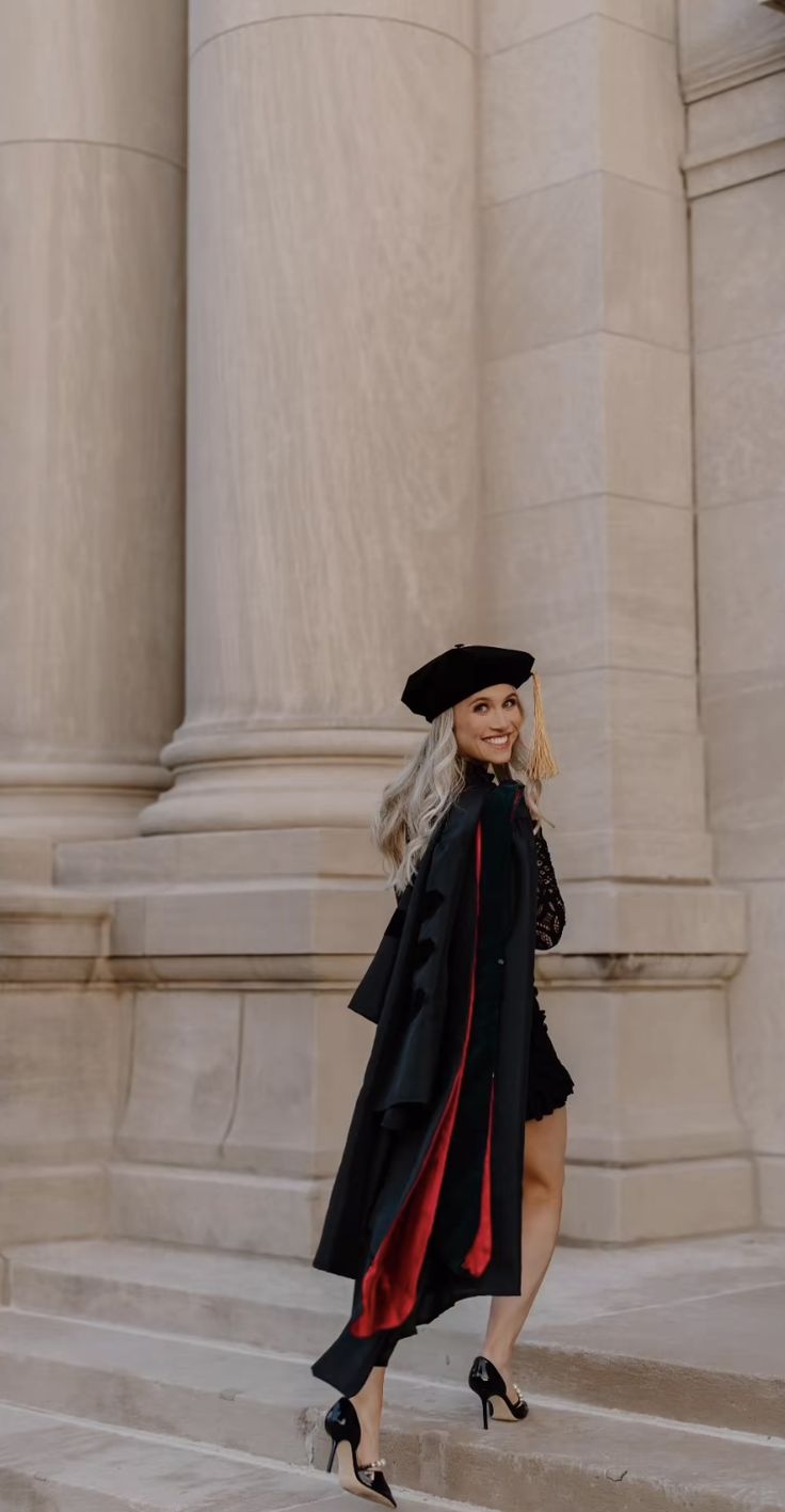 a woman in a graduation gown and hat standing on steps