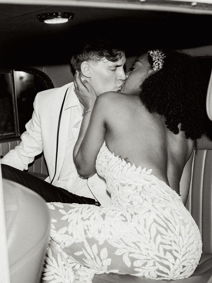 a man and woman kissing in the back of a car