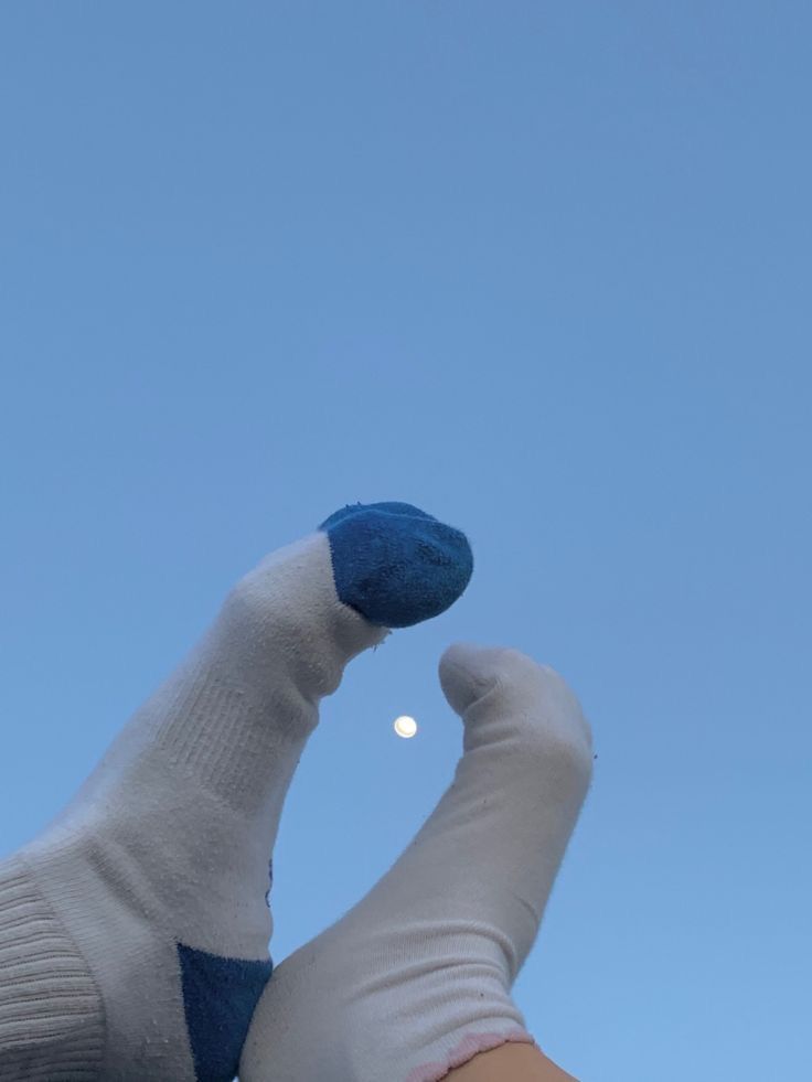 a person's hand with white and blue gloves holding a kite in the sky