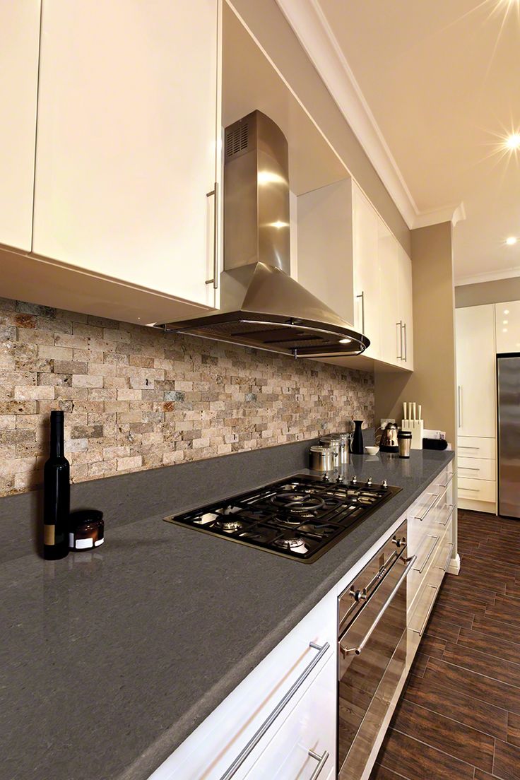 a kitchen with marble counter tops and white cabinets, along with a stainless steel range hood