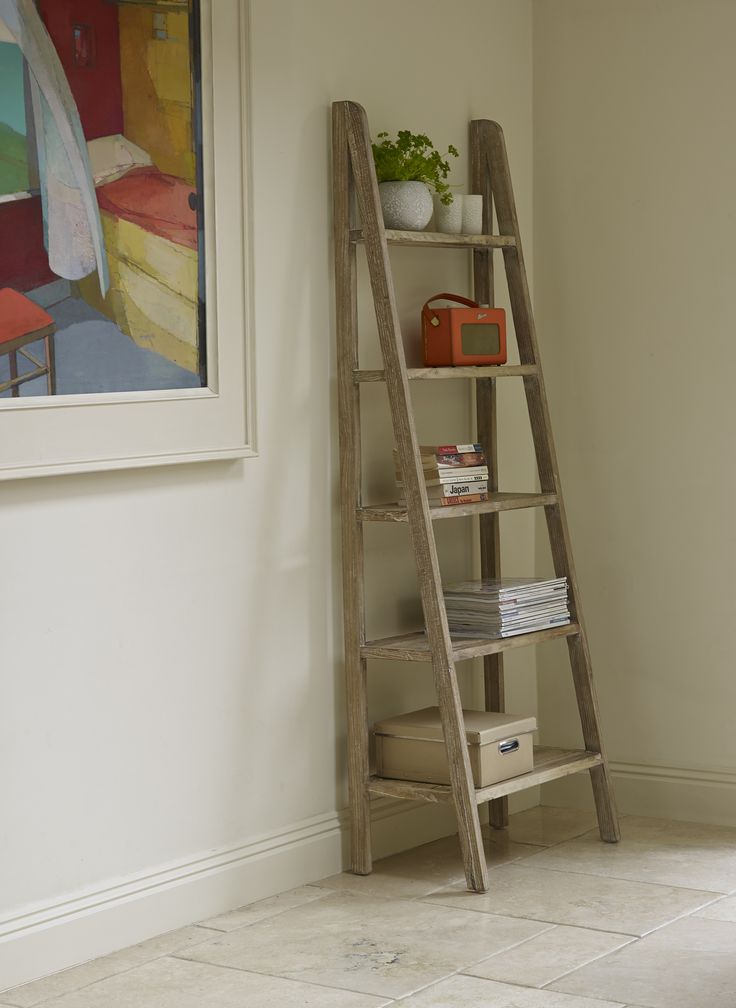 a wooden ladder leaning against a wall next to a shelf with books and magazines on it