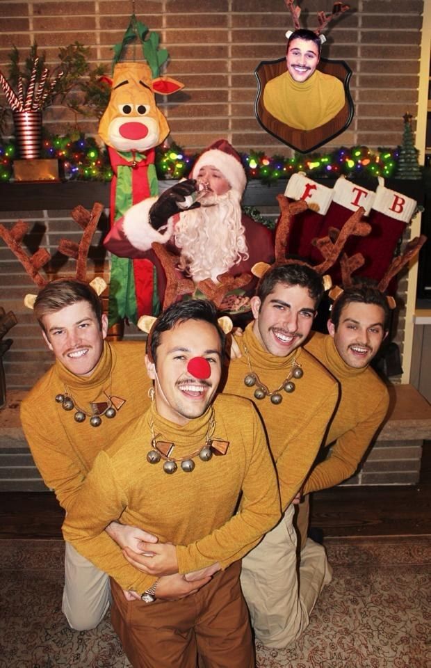 a group of men standing next to each other in front of a christmas tree with reindeers on it