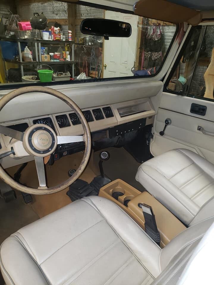 the interior of a car with white leather seats and steering wheel, in a shop