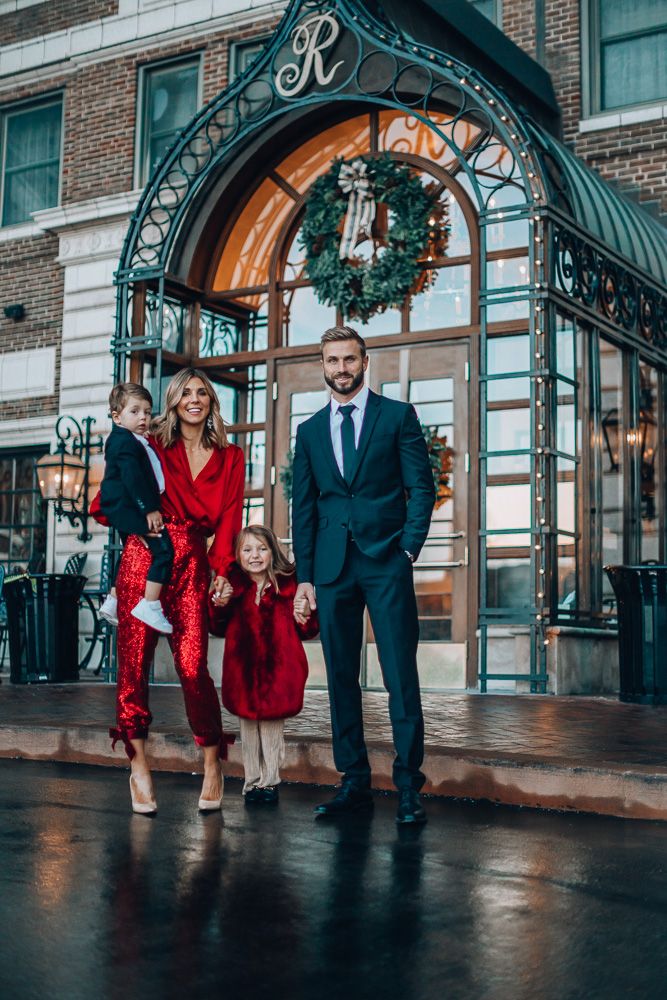 a man and two children are standing in front of the entrance to a building with a christmas wreath on it