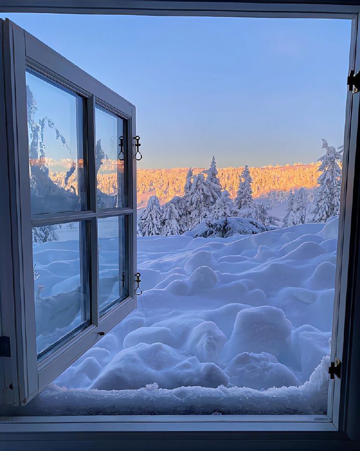 an open window looking out onto the snow covered mountains and trees in the foreground