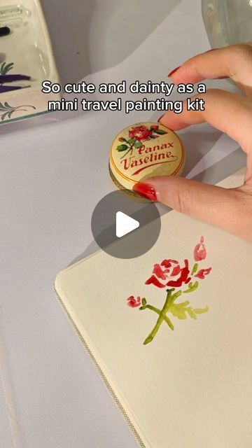 someone is painting flowers on a white table cloth