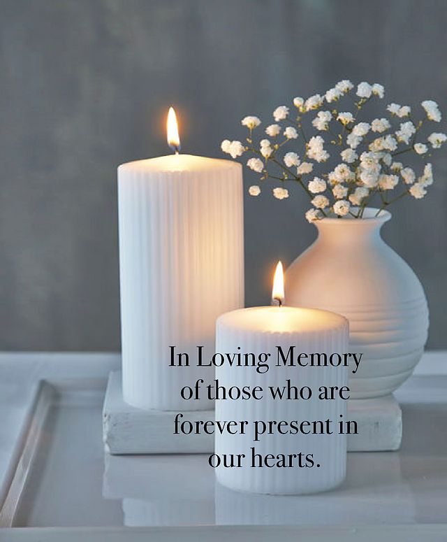 two white candles sitting next to each other on top of a tray with flowers in it