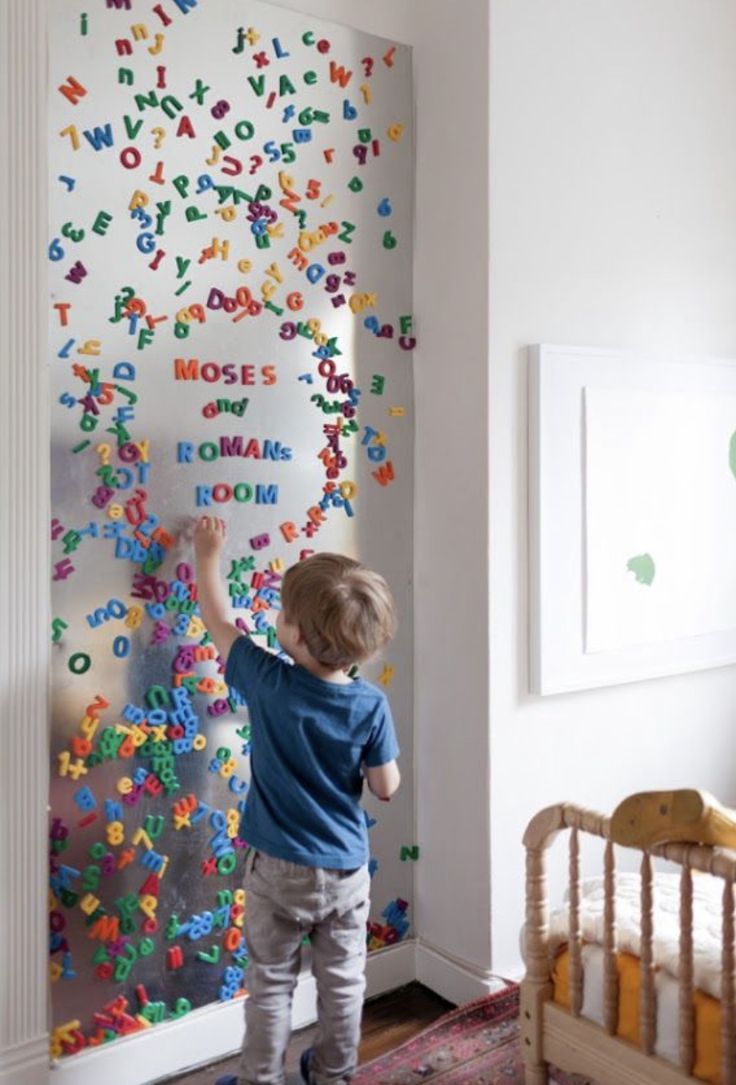 a little boy standing in front of a wall with letters on it