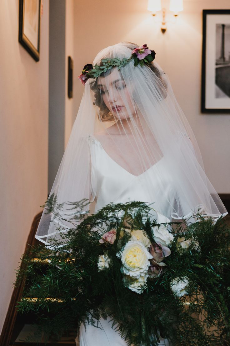 the bride is wearing a veil and holding her bouquet