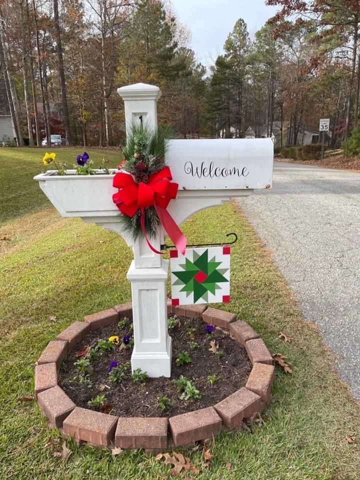 a mailbox decorated for christmas with a welcome sign and wreath in the front yard