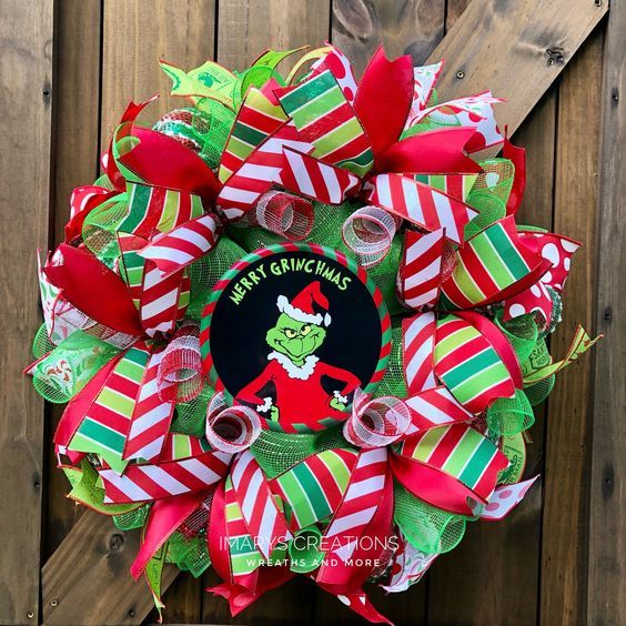 the grinch wreath is decorated with red, green and white ribbons on a wooden fence