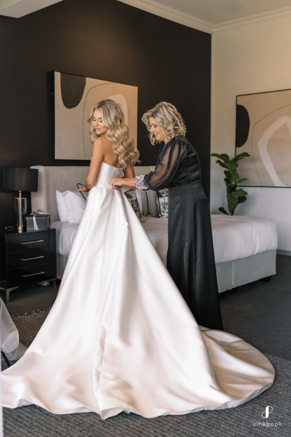 two women in black and white dresses standing next to each other, one wearing a wedding dress