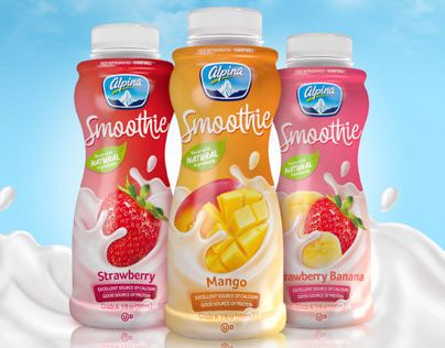 three bottles of smoothie drink with strawberries and mango on the side, in front of a blue sky