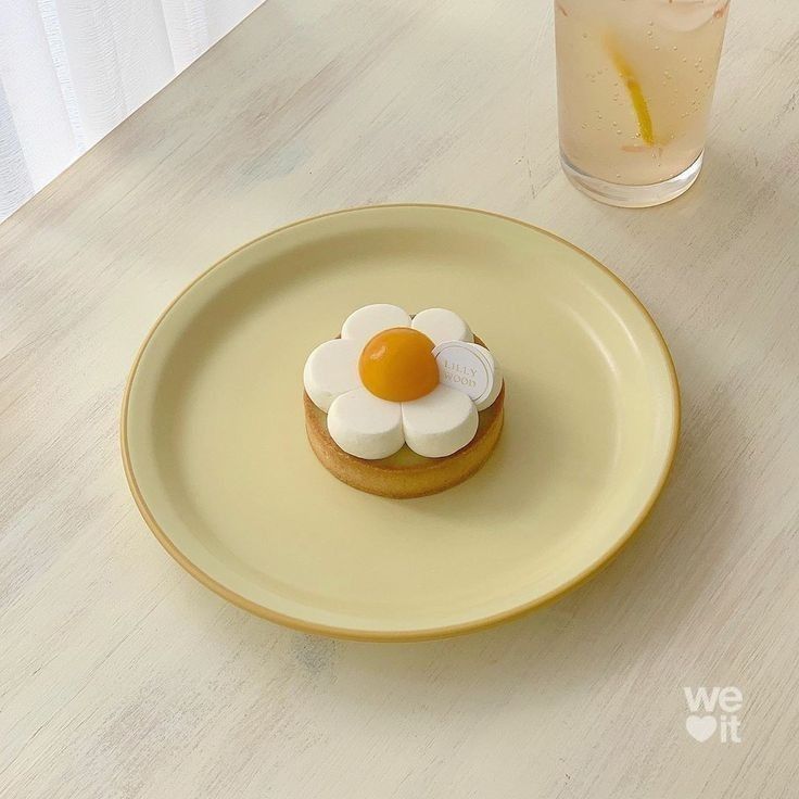 a plate with a small pastry on it next to a glass of water and an orange slice