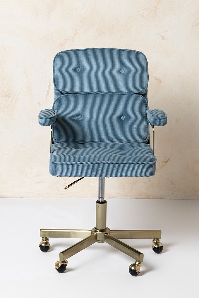 a blue office chair sitting on top of a white floor next to a beige wall