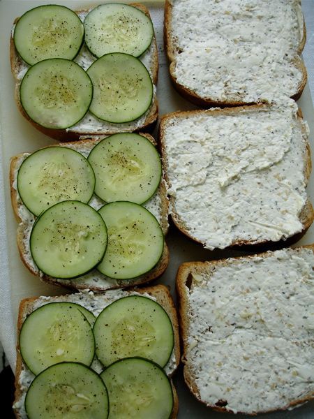 four slices of bread with cheese and cucumbers on them sitting in a tray