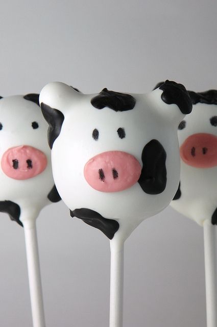 three marshmallows shaped like cows with black and white faces on them, sitting in front of a gray background