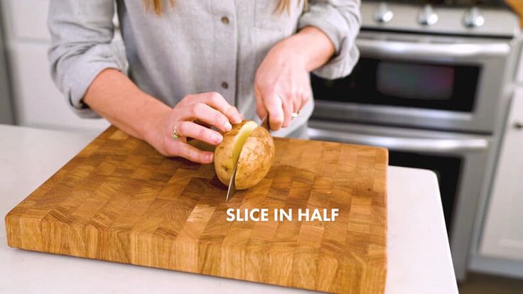 a woman cutting up some food on top of a wooden cutting board with the words slice in half