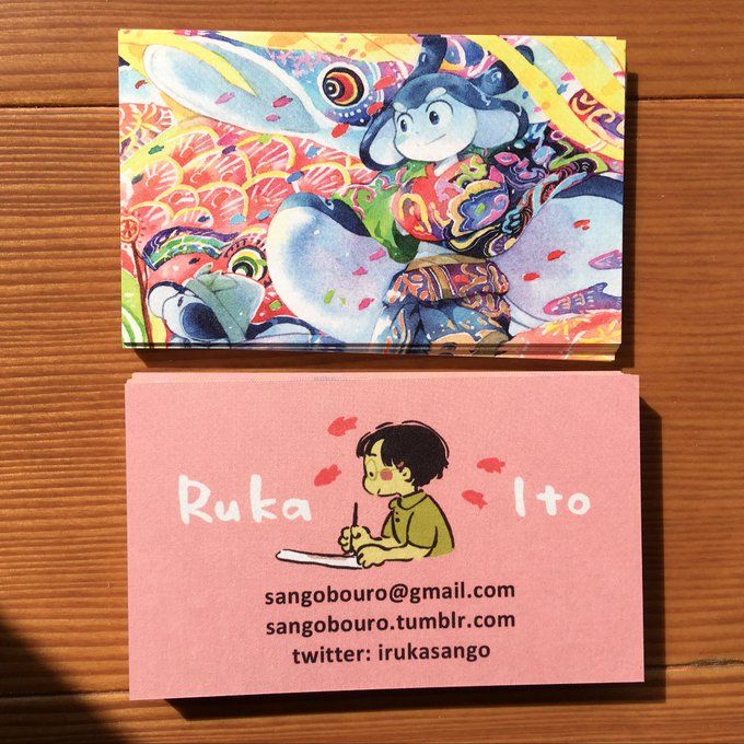 two business cards sitting on top of a wooden table next to each other with cartoon characters painted on them