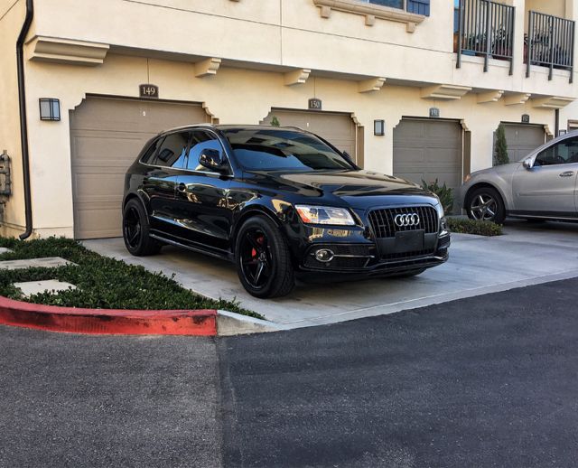 a black car parked in front of a building next to two silver and gray cars