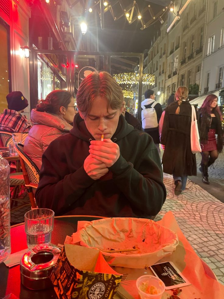 a man sitting at a table with food in front of him and his hands folded over his mouth