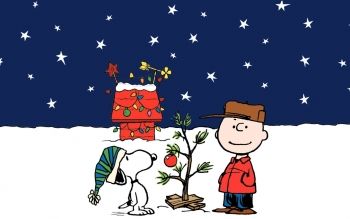 a charlie brown christmas card with a dog and a tree in the snow next to it