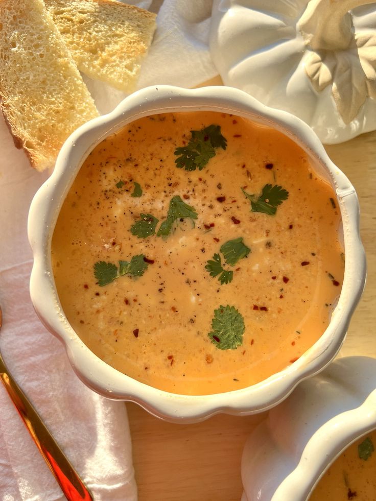 there is a bowl of soup and two slices of bread on the table next to it