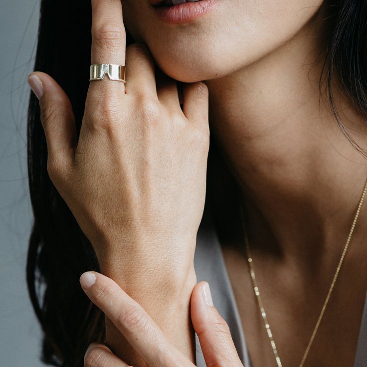 a close up of a person wearing a gold ring and holding her hand near her face