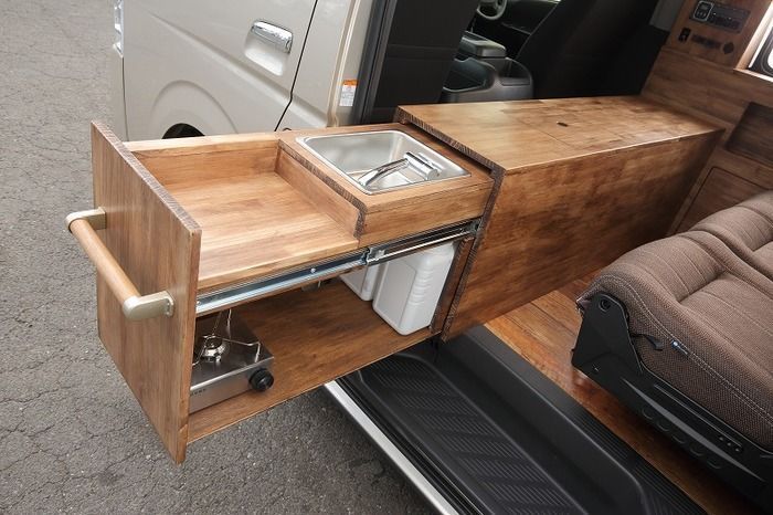 the interior of a camper van with an open sink and storage compartment on the side