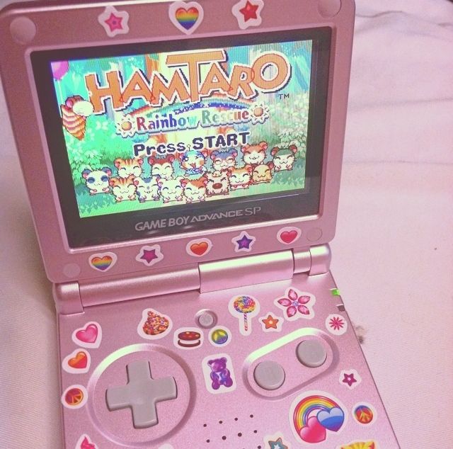 a pink nintendo game boy advance sitting on top of a white tablecloth covered surface