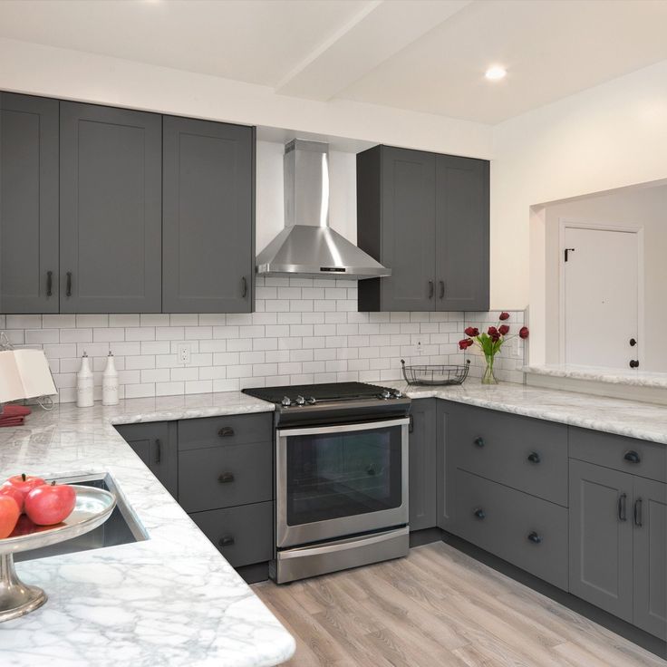 a kitchen with gray cabinets and marble counter tops