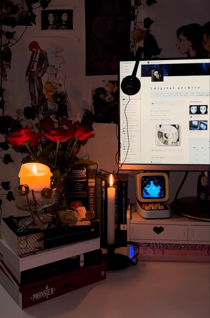 a computer monitor sitting on top of a desk next to a vase filled with flowers