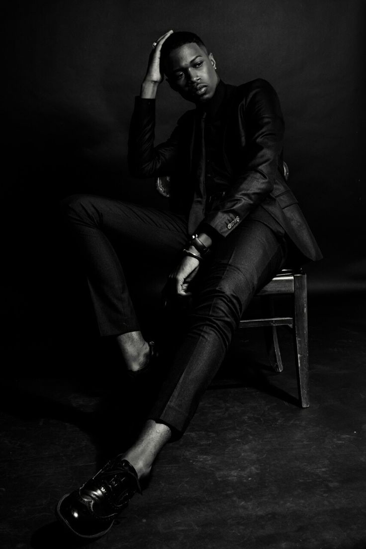 a black and white photo of a man sitting on a chair with his hand in his hair