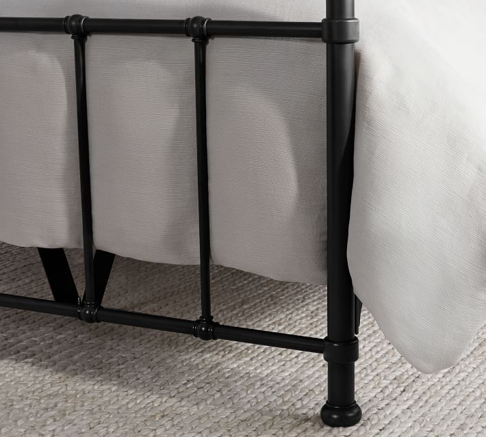 a black metal bed frame with white sheets