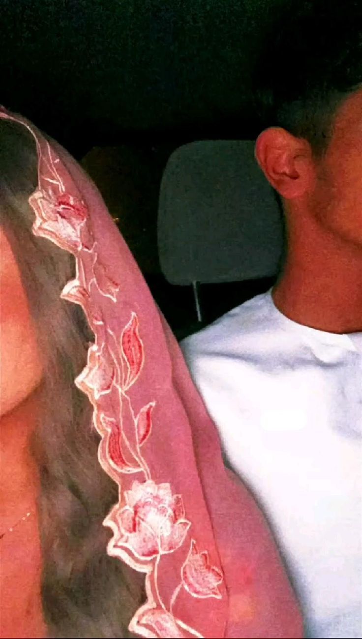 a man and woman sitting in the back seat of a car, one wearing a veil