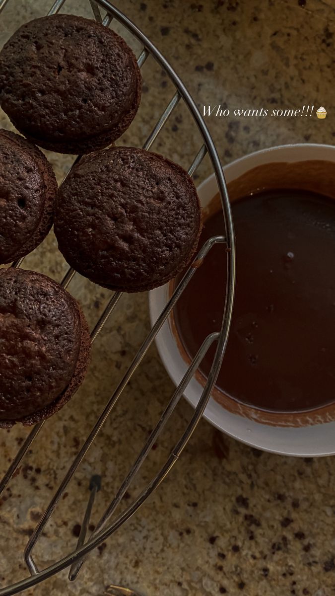 chocolate muffins cooling on a wire rack next to a cup of hot chocolate