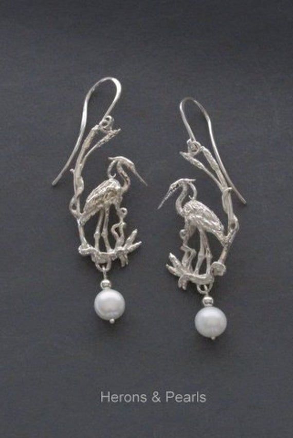 These sterling silver earrings represent this regal bird in an elegant design and spirit, accurately detailed in its natural setting and rendered in the proper mirror image. A freshwater pearl accent completes the design and gives a suggestion to the color of this majestic creature. The complete piece with pearl hangs 1 3/4 inches below the ear finding. I enjoyed very much designing this piece and sculpting the form of the feathery fellow. However, I did not want to attach a ring to the head of Mirror Image, Earrings Photo, Silver Fashion, Sterling Silver Earrings, Fresh Water, Freshwater Pearls, Elegant Design, Silver Earrings, Etsy Earrings