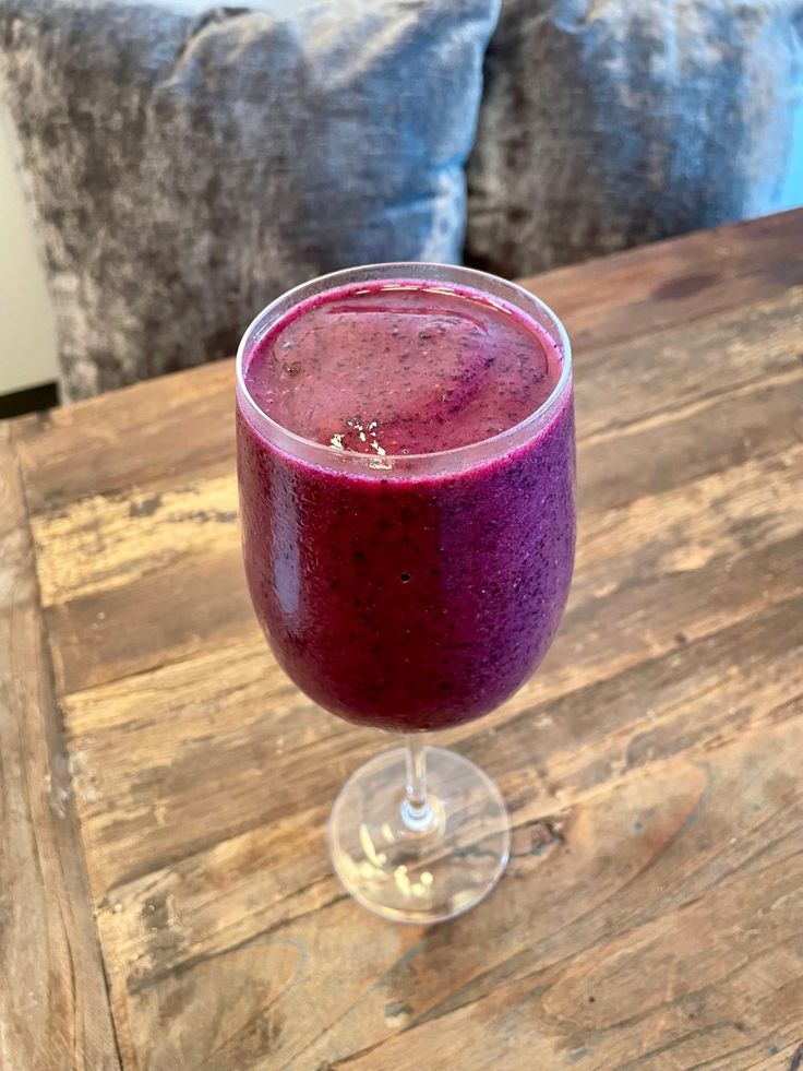 a purple drink sitting on top of a wooden table