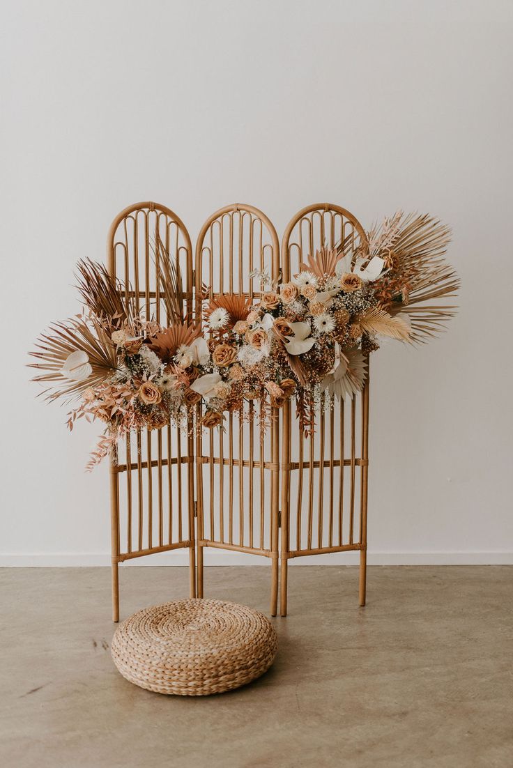 an arrangement of dried flowers and plants in wicker chairs