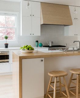 two stools are in front of the kitchen island with fruit on it and an oven